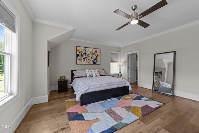 bedroom with multiple windows, ornamental molding, baseboards, wood finished floors, and ceiling fan