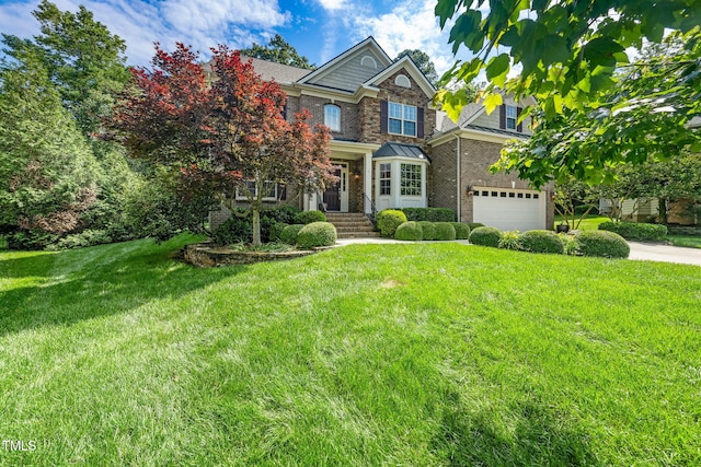view of front of house with an attached garage, a front yard, stone siding, driveway, and brick siding