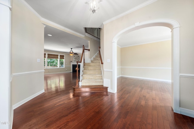 entryway featuring arched walkways, wood-type flooring, stairway, crown molding, and baseboards