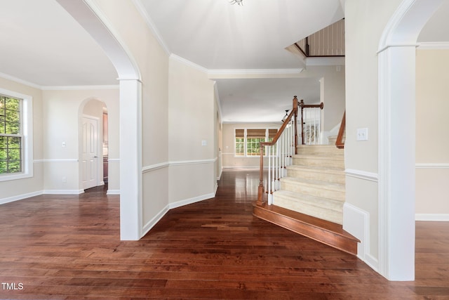 entrance foyer featuring plenty of natural light, wood finished floors, arched walkways, ornamental molding, and stairway