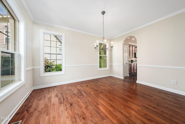 unfurnished room with a chandelier, dark wood-style floors, arched walkways, baseboards, and crown molding