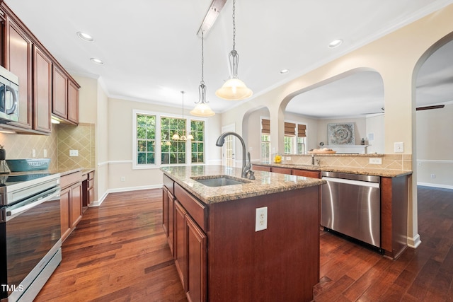 kitchen featuring stainless steel appliances, a sink, arched walkways, dark wood-style floors, and light stone counters