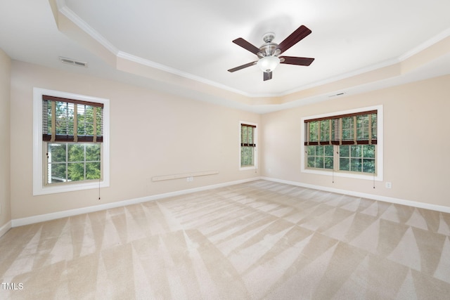 spare room with a tray ceiling, crown molding, carpet flooring, baseboards, and a ceiling fan