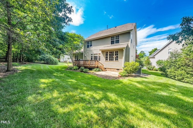 rear view of house with crawl space, a wooden deck, and a lawn