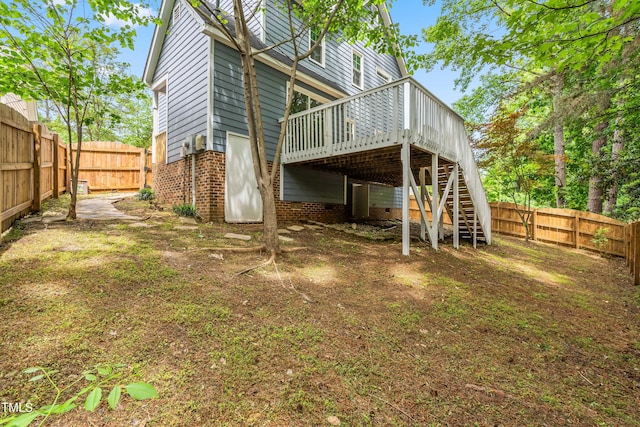 back of house featuring stairs, a wooden deck, a fenced backyard, and brick siding