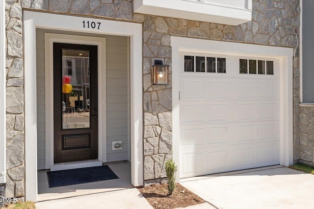 doorway to property with stone siding and concrete driveway