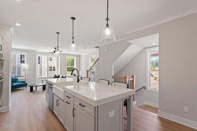 kitchen featuring a sink, a kitchen breakfast bar, light wood-style flooring, light countertops, and hanging light fixtures