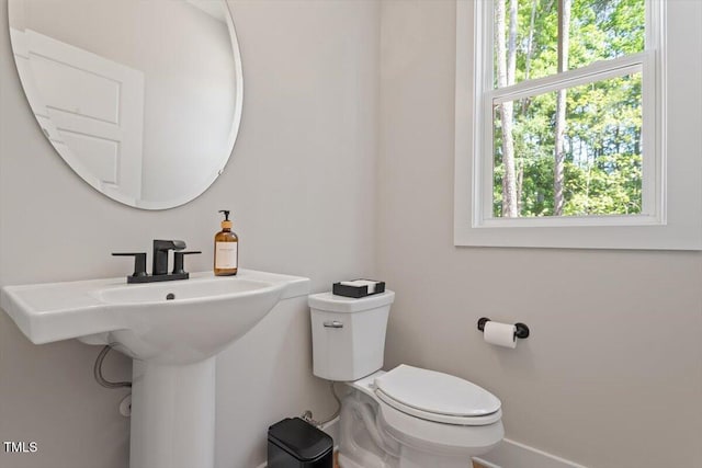 bathroom with toilet, plenty of natural light, and baseboards