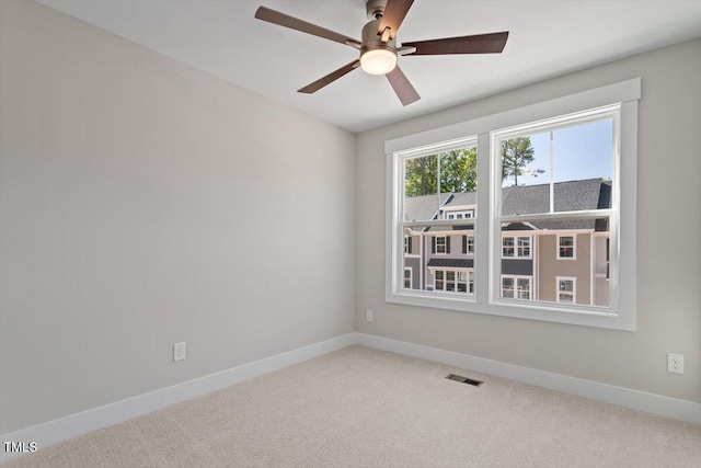 carpeted spare room with ceiling fan and baseboards