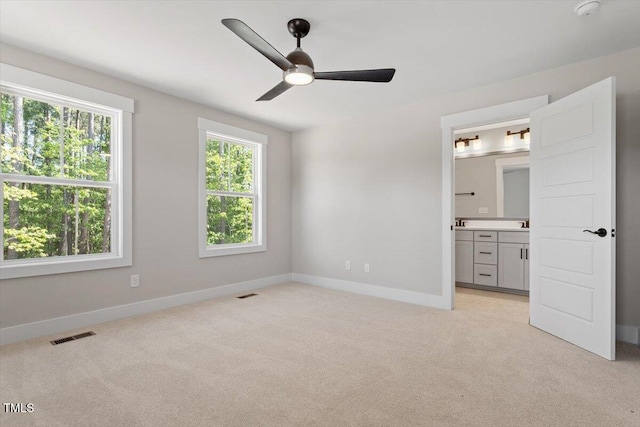 unfurnished bedroom with light colored carpet, baseboards, and ensuite bathroom