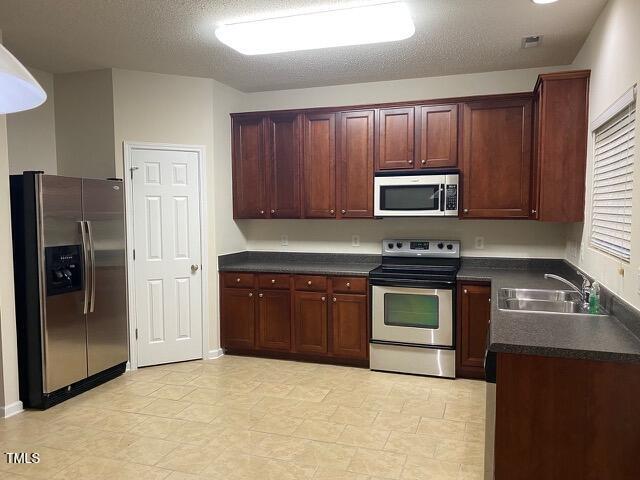 21 Suncrest Ct, Durham, NC 27703 - kitchen featuring appliances with stainless steel finishes, a sink, dark countertops, and a textured ceiling