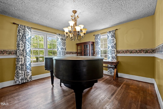 detailed view of a chandelier, baseboards, wood finished floors, and a textured ceiling