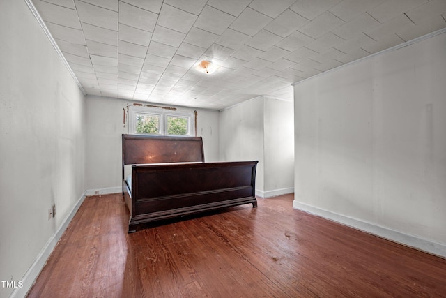 bedroom with hardwood / wood-style flooring, crown molding, and baseboards