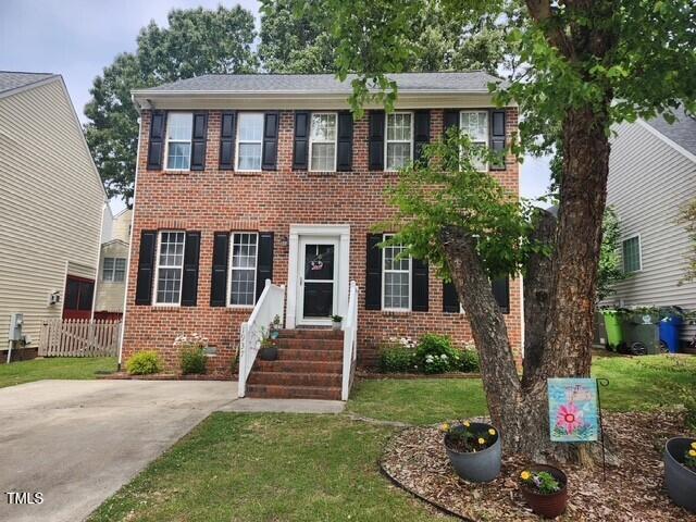 colonial home featuring entry steps and brick siding