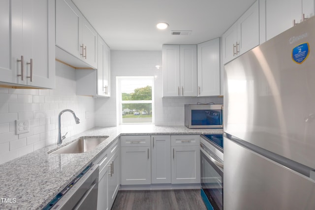 1917 Tucker St, Burlington, NC 27215 - kitchen featuring appliances with stainless steel finishes, a sink, dark wood finished floors, white cabinetry, and light stone countertops