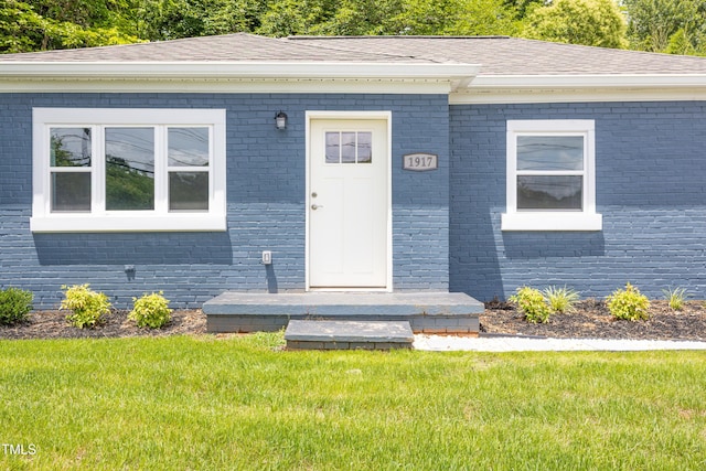 1917 Tucker St, Burlington, NC 27215 - doorway to property with brick siding, a lawn, and a shingled roof