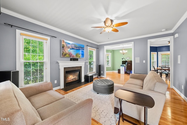 living area with light wood-style flooring, ceiling fan, a fireplace with flush hearth, and ornamental molding