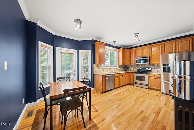 kitchen with stainless steel appliances, a sink, light countertops, tasteful backsplash, and crown molding