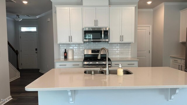 3112 Star Gazing Ln, Durham, NC 27703 - kitchen featuring stainless steel appliances, crown molding, dark wood finished floors, tasteful backsplash, and a sink