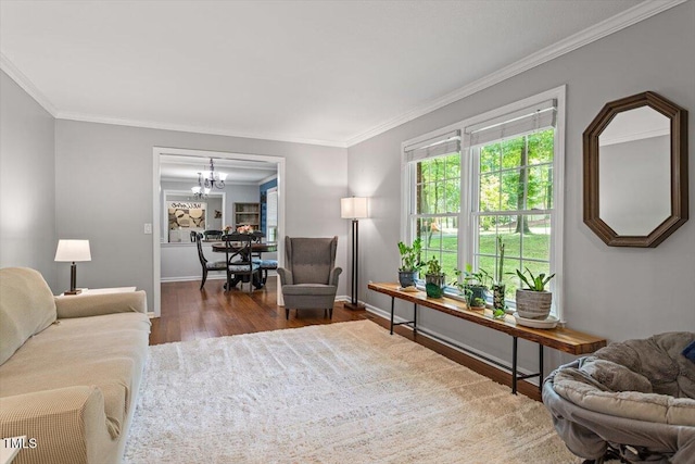 living area with a chandelier, crown molding, wood finished floors, and baseboards