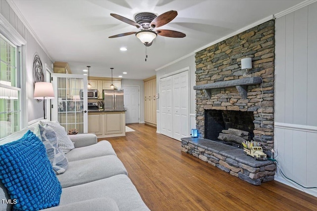 living room featuring ornamental molding, light wood finished floors, ceiling fan, a fireplace, and recessed lighting