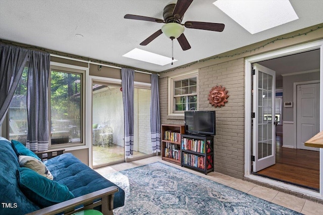 sunroom featuring a skylight, tile patterned flooring, and brick wall