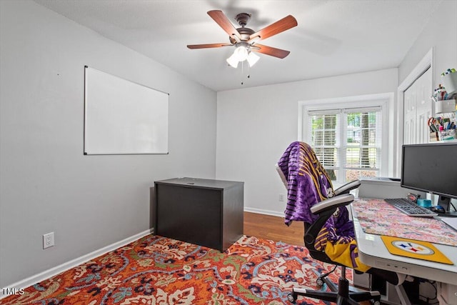 home office with a ceiling fan, wood finished floors, and baseboards