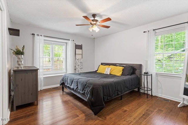 bedroom with wood finished floors, baseboards, a textured ceiling, and a ceiling fan