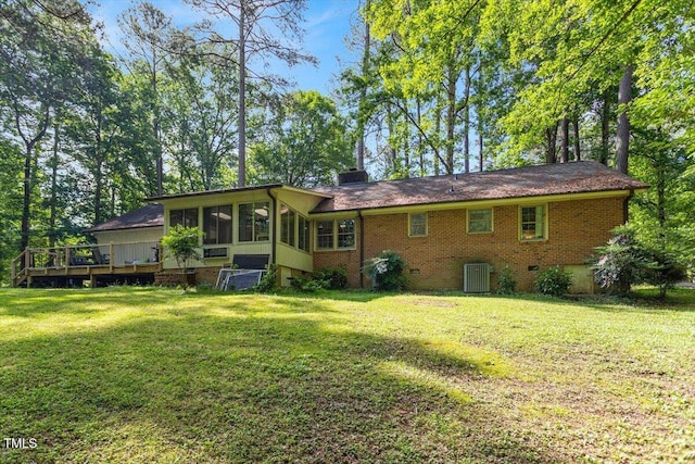 rear view of house featuring a sunroom, brick siding, a yard, and cooling unit