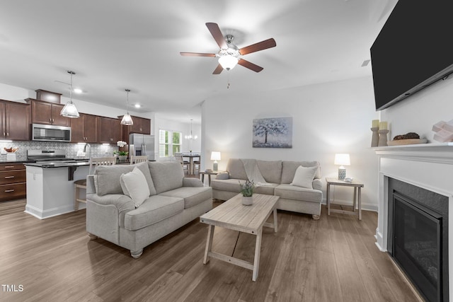 living room with wood finished floors, a ceiling fan, and a glass covered fireplace
