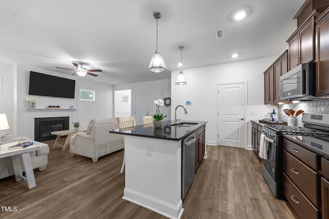 kitchen with stainless steel appliances, a sink, a ceiling fan, and dark wood finished floors