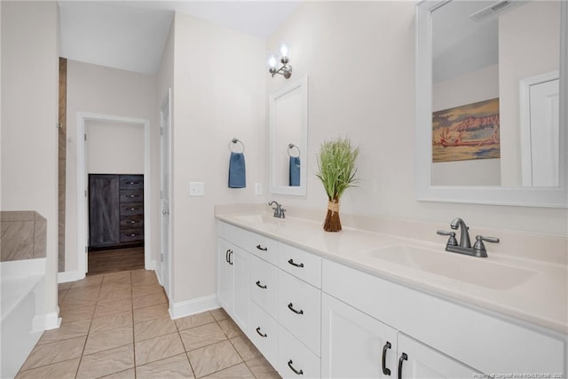 full bathroom featuring double vanity, a tub to relax in, and baseboards