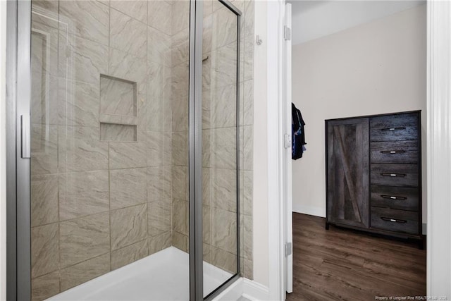 full bath with a stall shower, wood finished floors, and baseboards