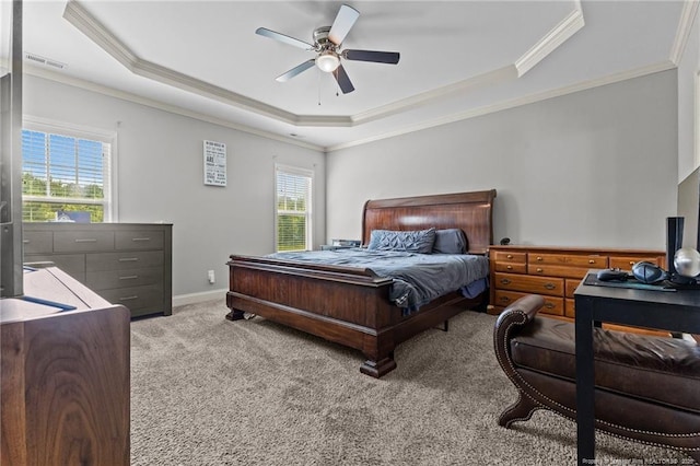 bedroom featuring a tray ceiling, crown molding, multiple windows, carpet, and ceiling fan