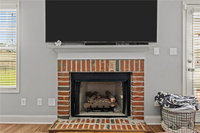 detailed view of a fireplace, baseboards, and wood finished floors