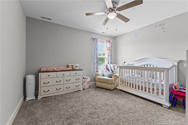 carpeted bedroom with a crib, ceiling fan, and baseboards