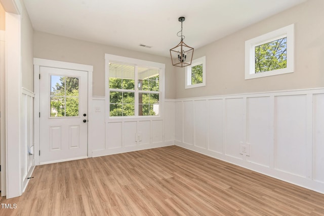 303 Godwin St, Selma, NC 27576 - unfurnished dining area featuring a decorative wall, light wood-style floors, wainscoting, and a chandelier
