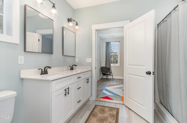 303 Godwin St, Selma, NC 27576 - full bathroom featuring double vanity, toilet, wood finished floors, and curtained shower
