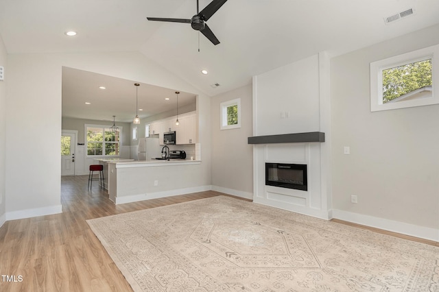 303 Godwin St, Selma, NC 27576 - unfurnished living room featuring healthy amount of natural light, light wood-style floors, ceiling fan, recessed lighting, and a glass covered fireplace