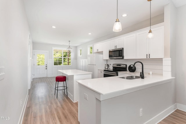 303 Godwin St, Selma, NC 27576 - kitchen with stainless steel appliances, a sink, a center island, light wood-type flooring, and light countertops