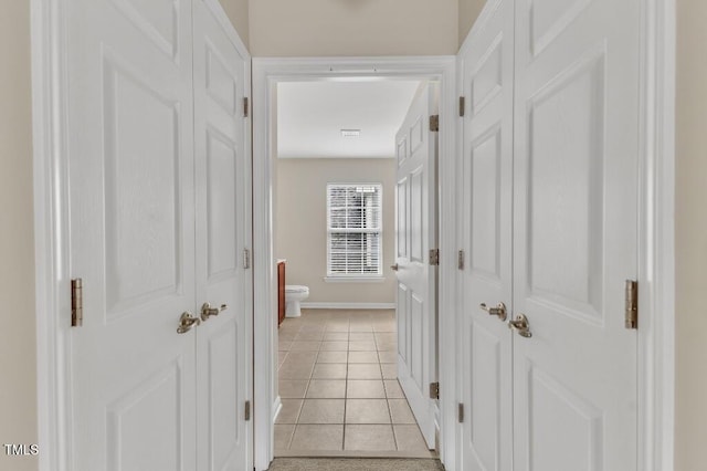 corridor with baseboards and light tile patterned flooring