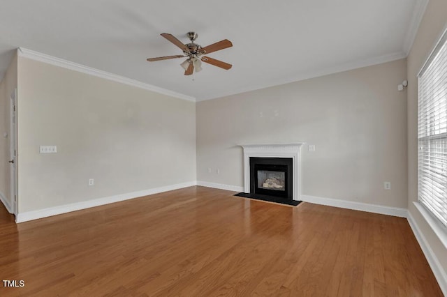 unfurnished living room featuring ceiling fan, wood finished floors, crown molding, a fireplace with flush hearth, and baseboards