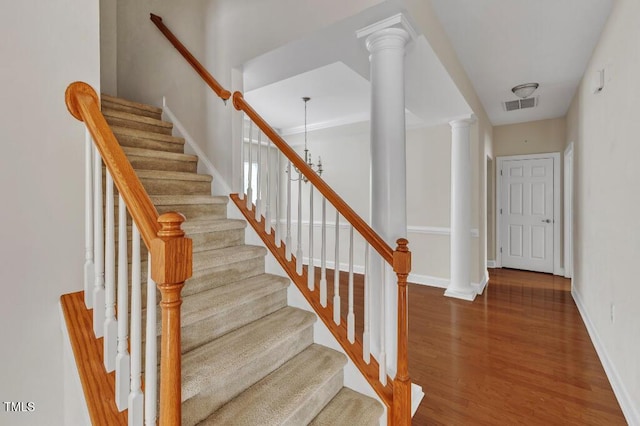 staircase with wood finished floors, ornate columns, and baseboards