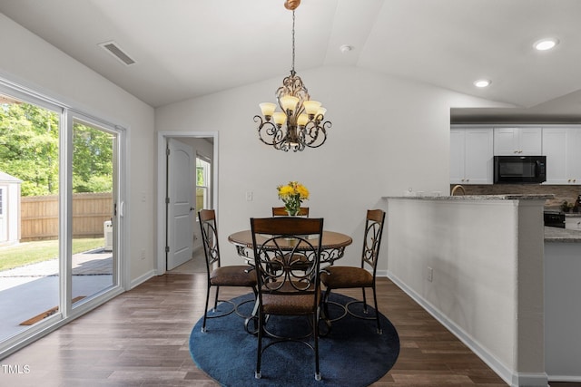 dining room featuring lofted ceiling, dark wood finished floors, healthy amount of natural light, a chandelier, and baseboards