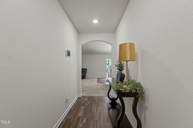 hallway featuring arched walkways, baseboards, dark wood-style flooring, and recessed lighting