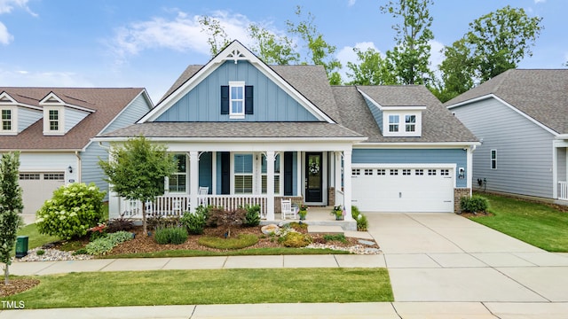 craftsman-style house featuring board and batten siding, a porch, a garage, driveway, and a front lawn