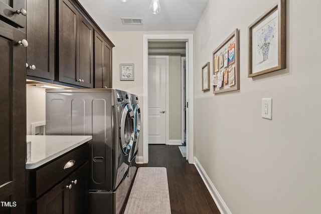 clothes washing area featuring washer and clothes dryer, cabinet space, dark wood finished floors, and baseboards