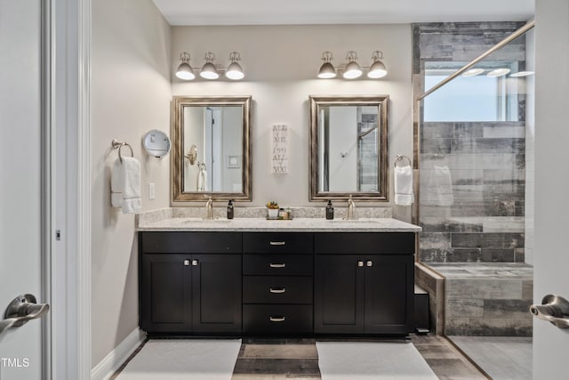 bathroom featuring a tile shower, double vanity, and wood finished floors