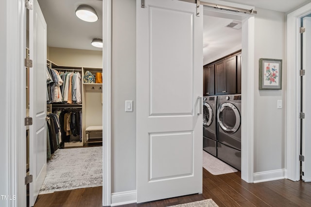 laundry area with washing machine and clothes dryer, cabinet space, dark wood-type flooring, and baseboards