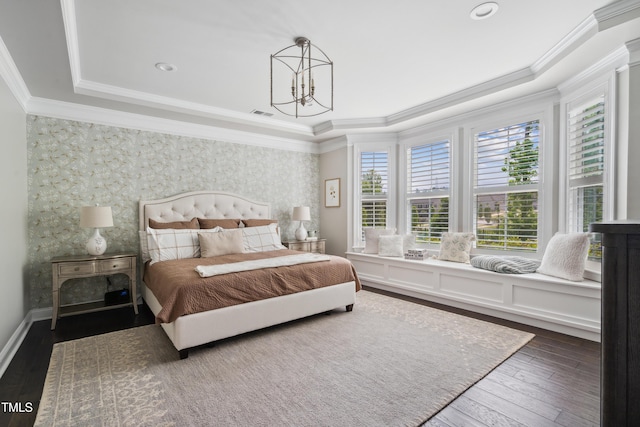 bedroom featuring wallpapered walls, a tray ceiling, an accent wall, crown molding, and dark wood finished floors